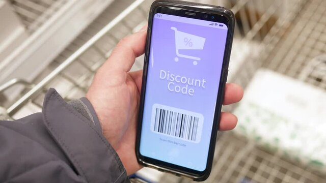 Holding a mobile phone with a discount coupon code while being at the store.