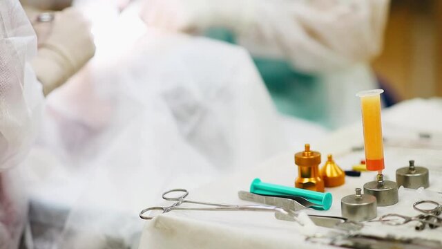 Table with surgical instruments for liposuction and lipofilling, cannulas, clamps, filter adapters.