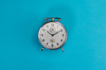 top view of vintage chrome alarm clock on light blue background