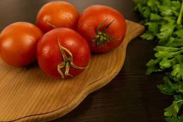 Red tomatoes on a wooden board and a dark textured wood background. With herbs.
Eco-friendly tomatoes. Fresh tomatoes. Tomatoes with water drops