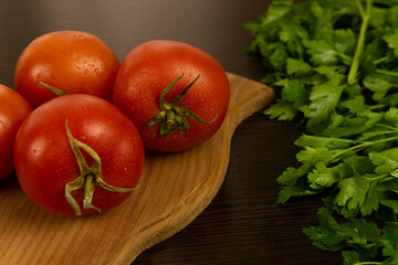 Red tomatoes on a wooden board and a dark textured wood background. With herbs.
Eco-friendly tomatoes. Fresh tomatoes. Tomatoes with water drops
