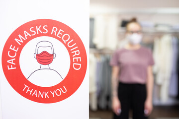Part of wall in clothing department with announcement about protective masks