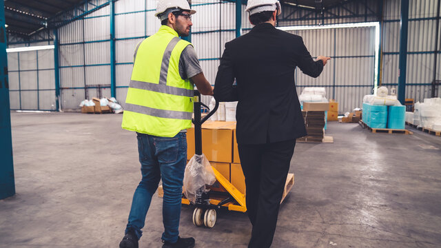 Factory workers deliver boxes package on a pushing trolley in the warehouse . Industry supply chain management concept .