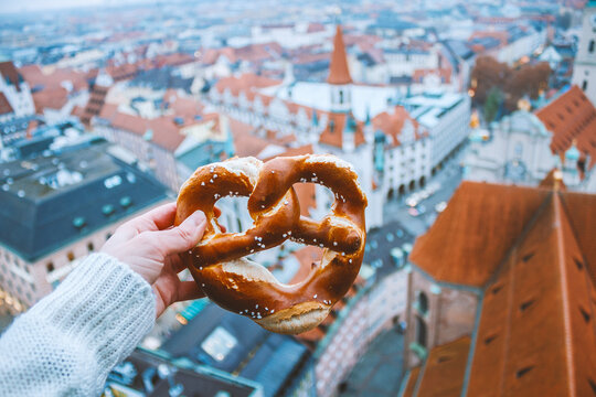 Hand with bretzel on the background of the panorama of Munich. Germany in winter.