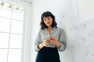 Female architect in office using mobile phone