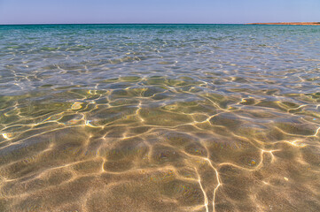 crystal clear sea water in shallow water with sun glare abstract background blur in motion