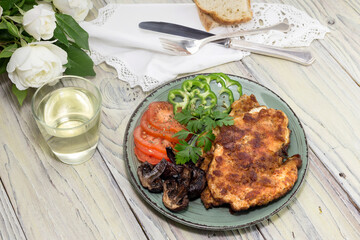 Schnitzel from chicken breast, vegetables and a glass of wine on a wooden table close-up