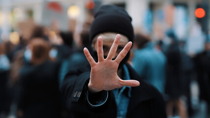 Stop. Young woman with face mask stoping camera with outstretched hand. Demonstation and protest. High quality photo