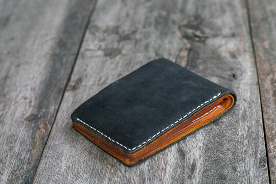 Black leather bifold money and card wallet on wood