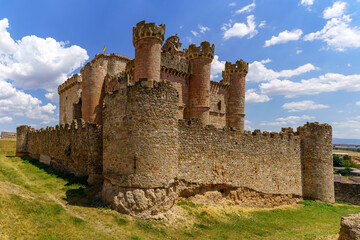 Fototapeta premium Castillo medieval en la provincia de Segovia con torres altas de piedra en día soleado con nuebes blancas. Turégano España.