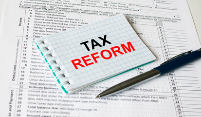 Obraz premium Notepad with text Tax Form lying on financial tables with a pen