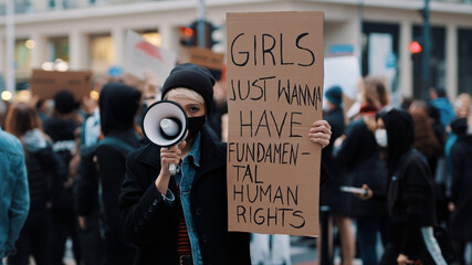 Girls just wanna have fundamental human rights. Woman march anti-abortion protest, woman holding banner and spaking into the megaphone. High quality photo - obrazy, fototapety, plakaty