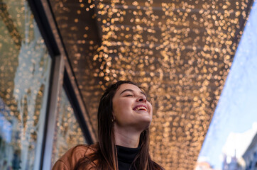 mujer con ropa de invierno con luces de navidad de fondo 