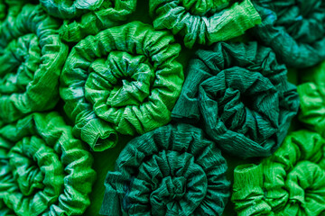 Fototapeta premium Abstract green pattern, background. Ornament from fabric with curls, twisted tubes