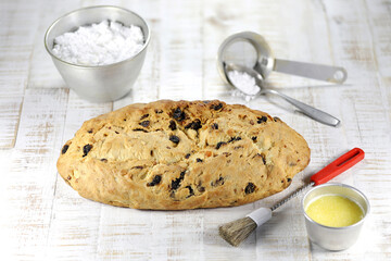 freshly baked traditional Saxon Christmas Stollen with some baking ingredients to be finished with powdered sugar