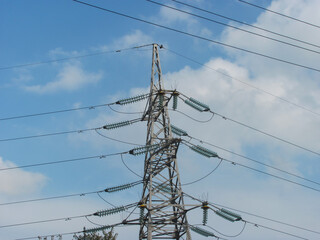 power line support with wires against blue sky with white clouds