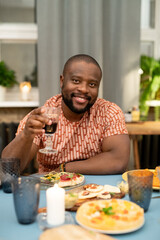 Happy young African man cheering up with glass of red wine in front of camera