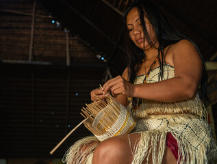indigenous woman from the uitoto tribe of the colombian amazon weaving a traditional basket