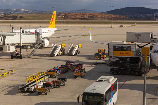 Luggage carrier, ambulift, air jetty, and passenger boarding bridge on airport apron of Sabiha Gokcen Airport. Sabiha Gokcen, Turkey - February 16 2020.
