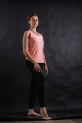 Beautiful young woman dressed in sportswear studio portrait on black background.