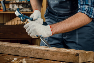 male carpenter hammers wood with a chisel. carpentry tools.
