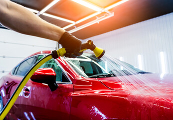 Naklejka premium Service worker washing car on a car wash.