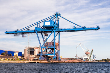 Fototapeta na wymiar Massive blue crane unload cargo in a seaport in Sweden