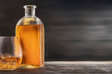 a bottle and a steamed glass with alcohol whiskey or Bourbon Scotch on the table, drops on the...