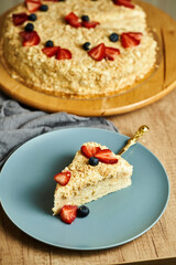Slice of napoleon cake on plate. Board with delicious tasty homemade cake on table. Wooden...