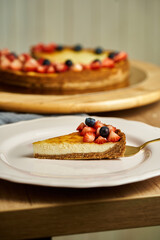 Slice of cheesecake on plate. Board with delicious tasty homemade cake on table. Wooden background.