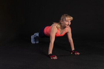 Fototapeta na wymiar Fitness on a step platform with a barbell with dumbbells. Going in for sports on a black background Happy smiling at the camera. exercise plank