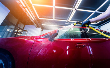 Obraz premium Service worker washing car on a car wash.