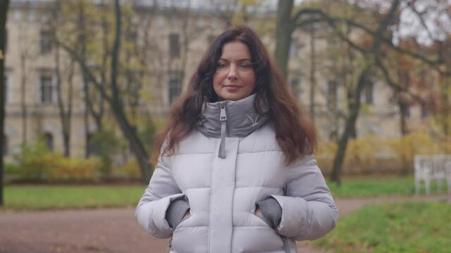 Attractive woman in warm coat walking in autumn park. Brunette woman in Catherine Park, Tsarskoye Selo, Saint Petersburg, Russia.