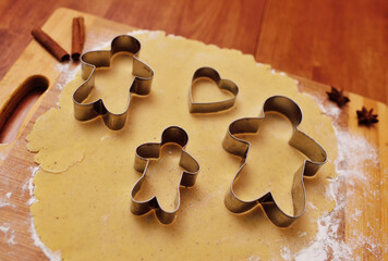 forms for baking gingerbread in the shape of a man and a heart on the background of a rolling pin...