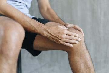 Young man suffer from knee pain, health problems and health care concept.
