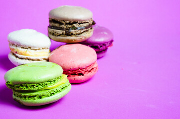 Obraz na płótnie Canvas Set of colorful French pasta cakes. Sweet macaroons with different flavors on a purple background, close up copy space