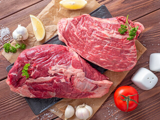 close-up of chunks of juicy raw beef on parchment. Vegetables and spices around. Food composition....