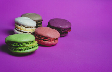 Set of colorful French pasta cakes.  Sweet macaroons with different flavors on a purple background,...
