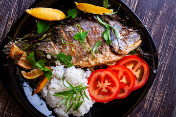 Fried gilthead with juicy fresh lemon and rice garnish and tomatoes close-up
