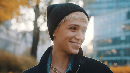 Portrait of young smiling woman with black hat and winter jacket in the city . High quality photo