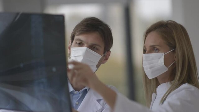 Team of doctors with protective facial masks examining xray in the office