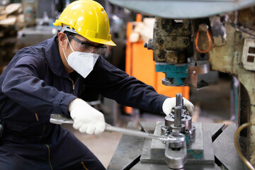 engineer man or factory worker wearing face mask for protect virus, using wrench to fix the machine
