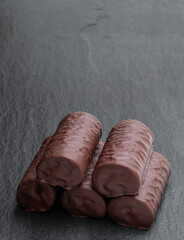 Chocolate sponge cake covered with milk chocolate on black stone background