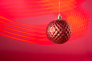Red Christmas ball on a red background and red light stripes in the form of a pattern