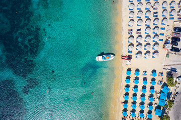 Aerial top down view to the umbrellas and the turquoise sea at the popular beach of Ornos, Mykonos island, Greece