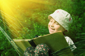 Learning always and everywher concept. Very happy young beauutifuul girl reading book outdoors in hammock in park