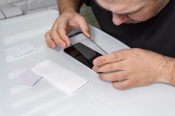 a man changes the protective glass on a smartphone