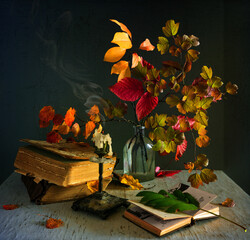 Still life with autumn leaves, extinguished candles and books. Vintage.