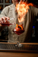 man add ingredients to glass with small pumpkin and pepper inside