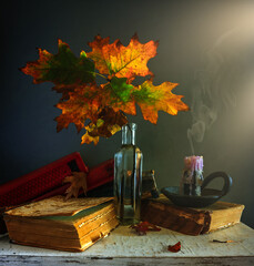 Still life with autumn leaves, extinguished candles and books. Vintage.